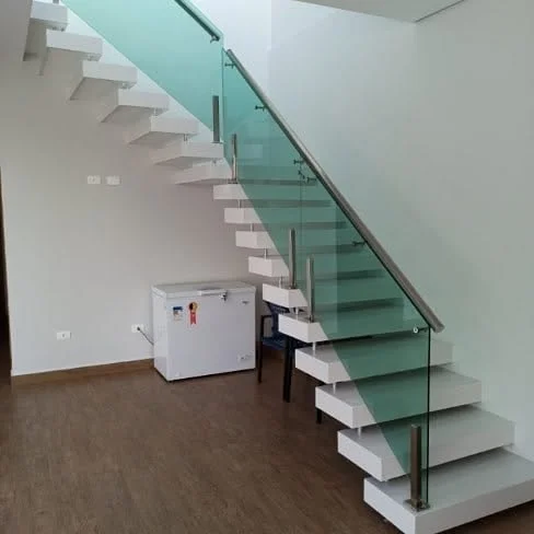 Escada interna real de alvenaria branca com degraus aparentes e guarda-corpo de vidro